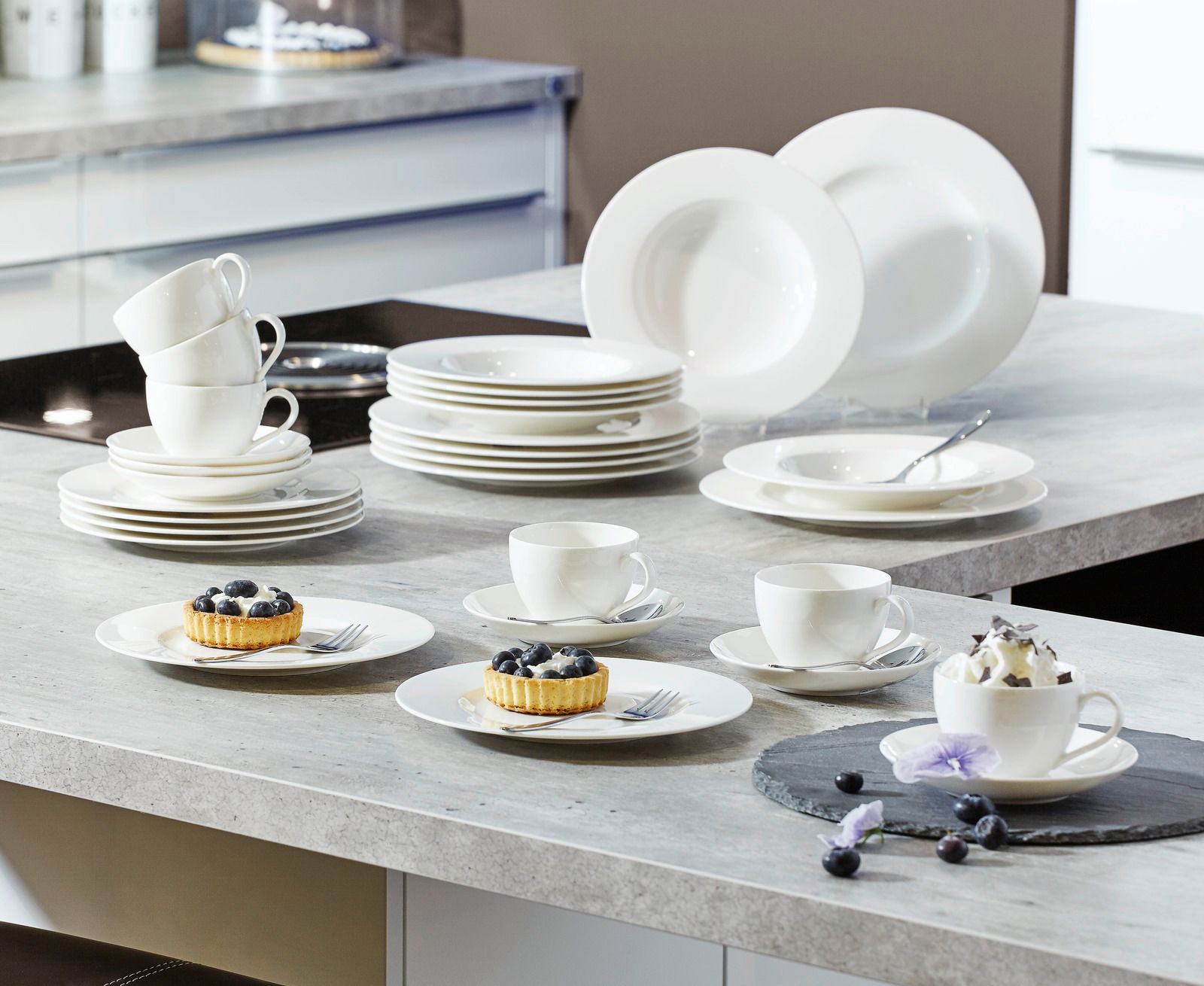 Villeroy & Boch Kombiservice Basic White 30-tlg. Ein 30-teiliges weißes Geschirrset, bestehend aus Tellern, Tassen und Schalen, auf einer Küchenarbeitsplatte präsentiert. Perspektive von oben.