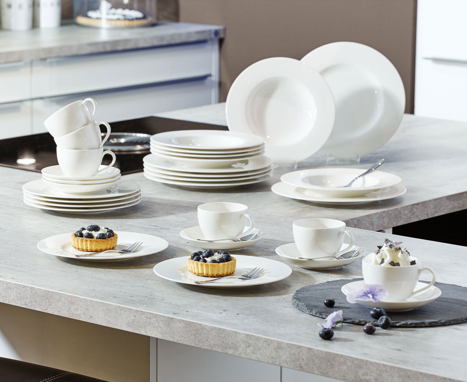 Villeroy & Boch Kombiservice Basic White 30-tlg. Ein 30-teiliges weißes Geschirrset, bestehend aus Tellern, Tassen und Schalen, auf einer Küchenarbeitsplatte präsentiert. Perspektive von oben.