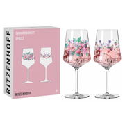 Zwei elegante Sprizzgläser mit floralen Motiven, gefüllt mit einem rosafarbenen Getränk, vor einer Verpackung mit ähnlichem Design. Frontalansicht.