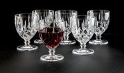Zes elegante wijnglazen van kristal, waarvan één gevuld met rode wijn, tegen een zwarte achtergrond. Vooraanzicht.