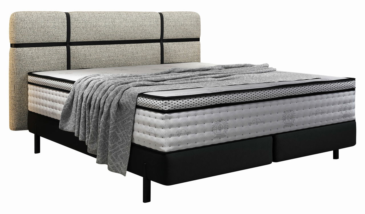 Boxspringbett mit gepolstertem Kopfteil und grauer Decke, seitliche Perspektive