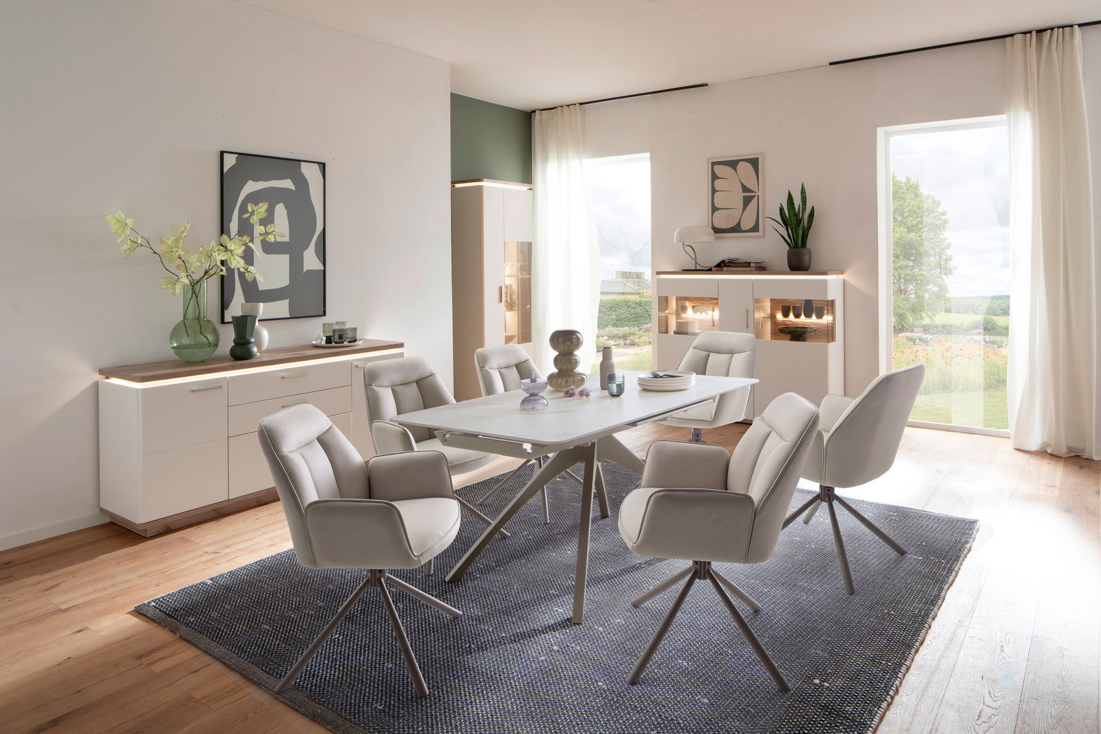 Zurbrüggen Sideboard PALERMO Esszimmer mit modernem Esstisch und sechs gepolsterten Stühlen, umgeben von Sideboards und Highboards mit LED-Beleuchtung, aus der Perspektive eines offenen, hellen Raumes mit Blick nach draußen.