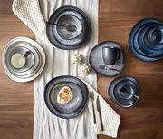 Vogelperspektive auf ein stilvolles, graues Kombiset Sören mit 10 Teilen, bestehend aus Tellern, Tassen und Schalen, auf einem Holztisch mit Tischläufer arrangiert.