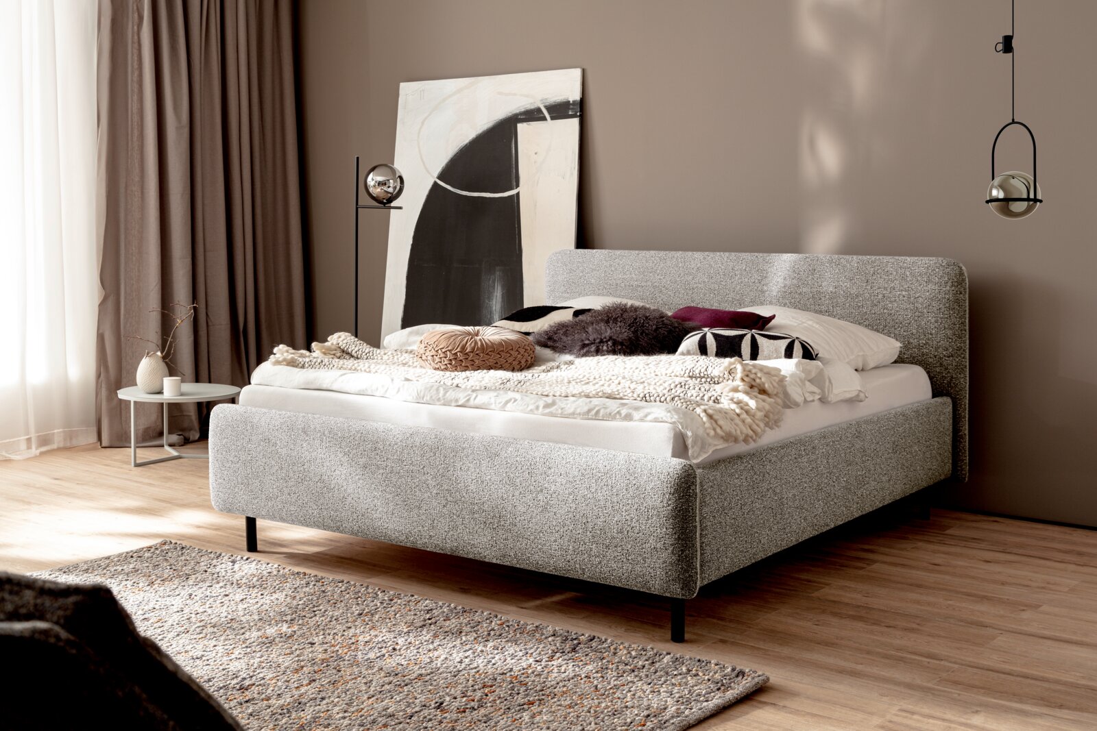 Modernes Polsterbett in einem stilvoll eingerichteten Schlafzimmer, seitliche Perspektive.