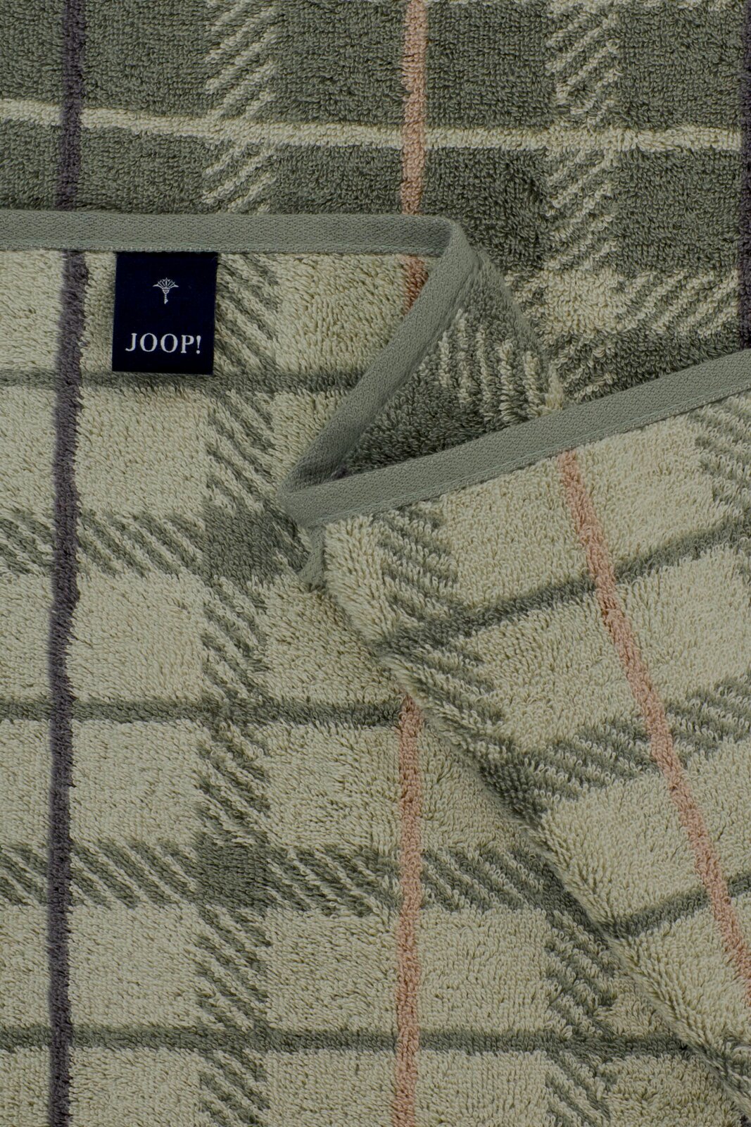 Detailaufnahme von oben auf ein JOOP! Frottier-Handtuch mit kariertem Muster und Blättermotiv in Grün- und Beigetönen, mit eingefasster Kante und Markenlabel