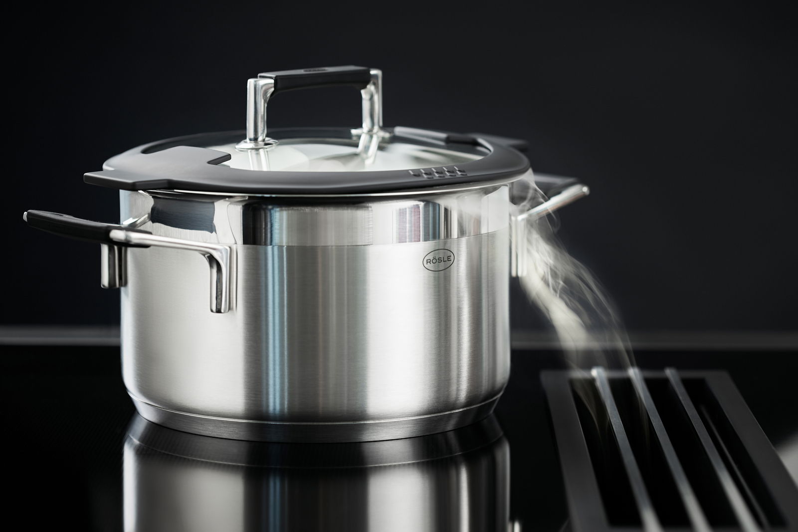 Edelstahlkochtopf mit Glasdeckel und Dampf, seitliche Perspektive