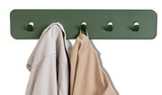 Grüne Garderobenleiste mit vier Haken, frontal abgebildet, zwei Kleidungsstücke hängen daran.