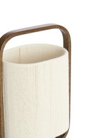Detailopname vanuit een licht verhoogd schuin vooraanzicht van een crèmekleurige cilindervormige lampenkap met fijne koordstructuur in een afgerond donkerhouten frame