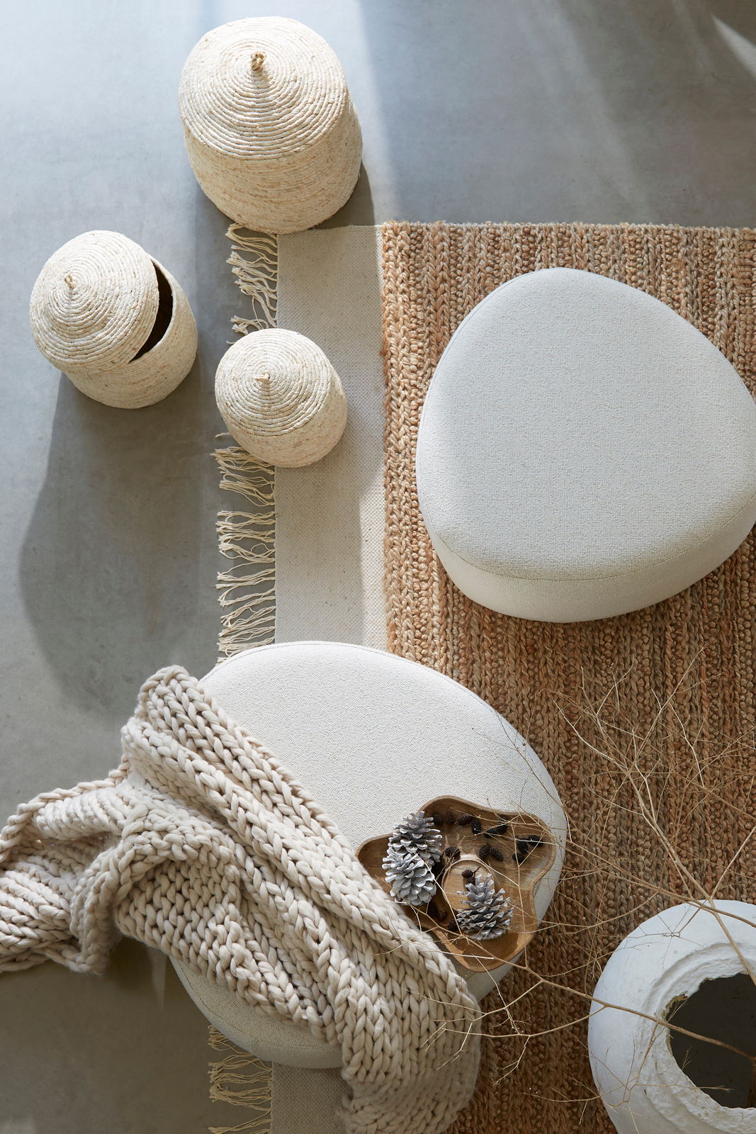 Sitzpuff in einer gemütlichen Wohnumgebung, von oben fotografiert, umgeben von geflochtenen Körben, einem Teppich und einer Decke.