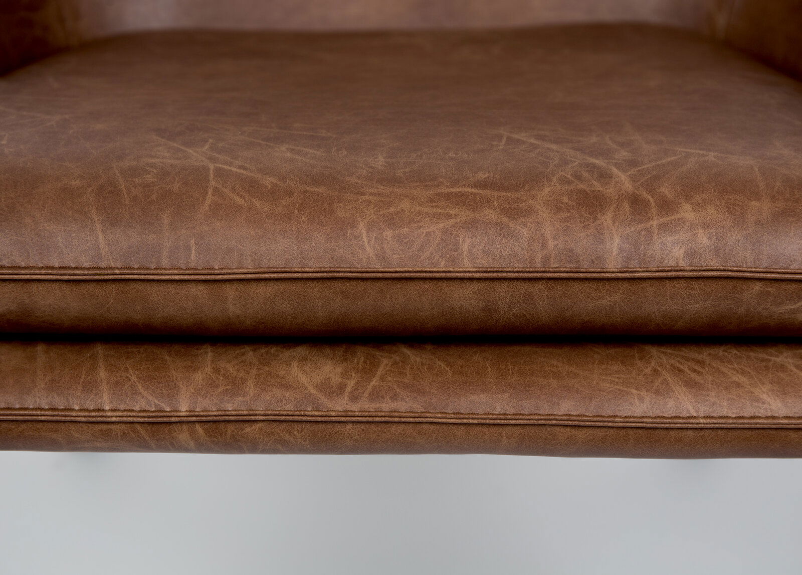 Nahaufnahme eines braunen Ledersesselsitzes von vorne