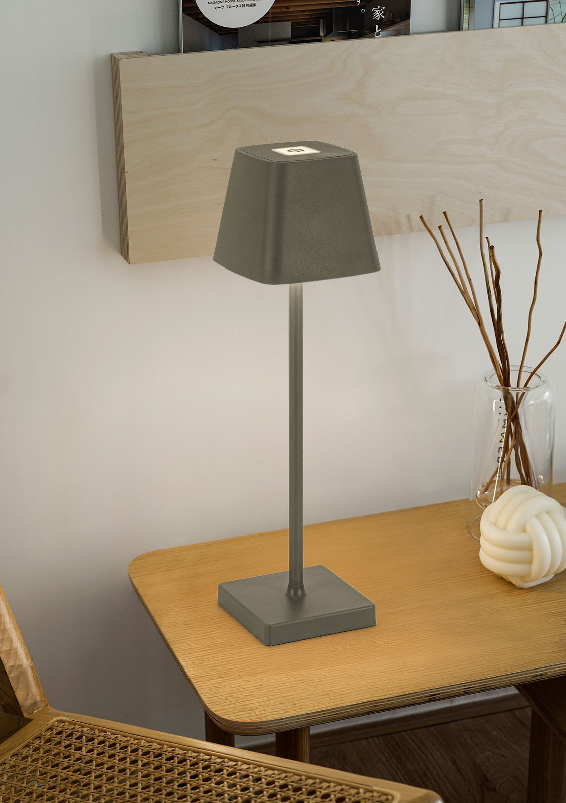 Moderne Akku-Tischleuchte in Grau auf einem Holztisch, seitliche Perspektive.