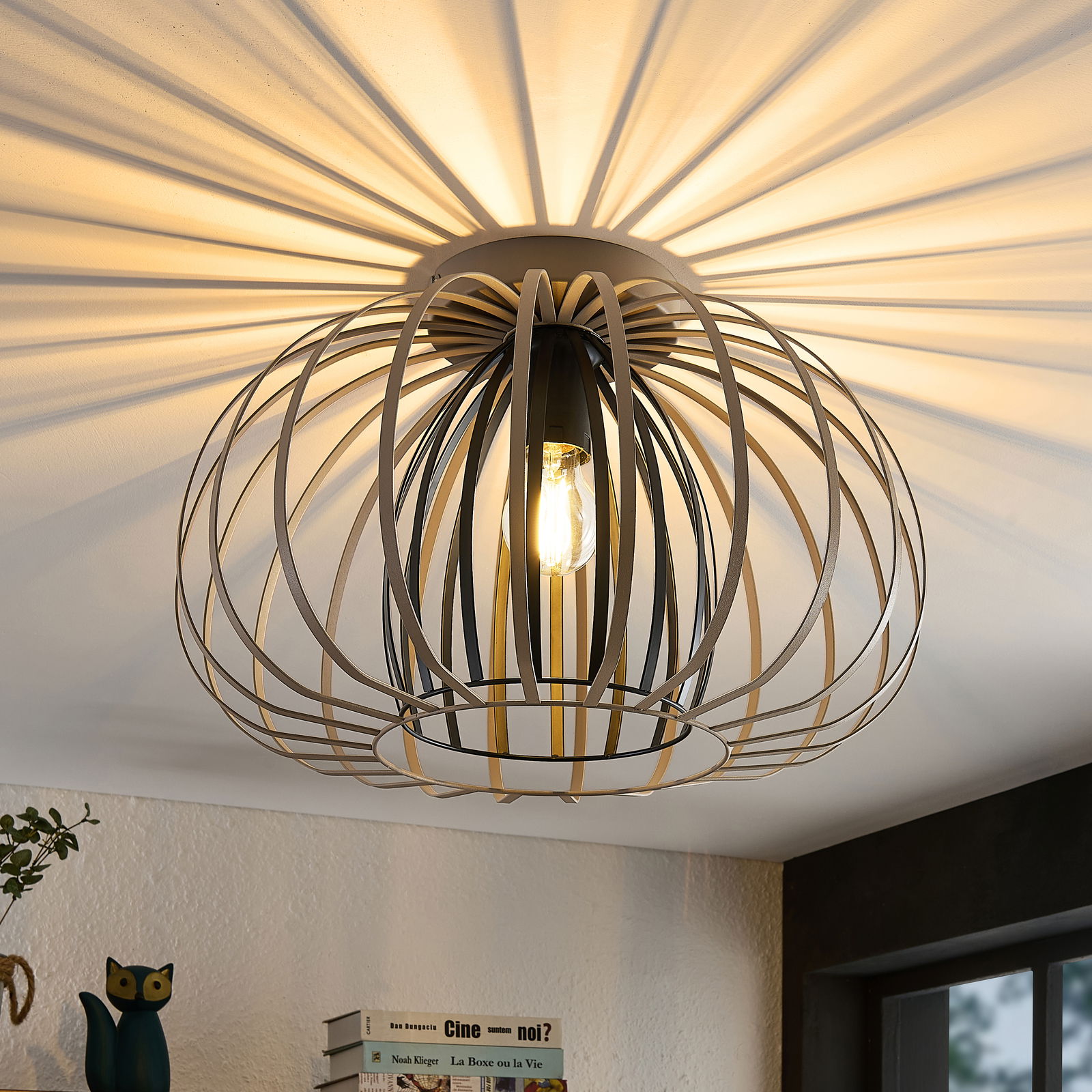 Moderne Deckenleuchte mit einem kugelförmigen, offenen Metallrahmen, der interessante Licht- und Schattenspiele an der Decke erzeugt. Perspektive von unten.