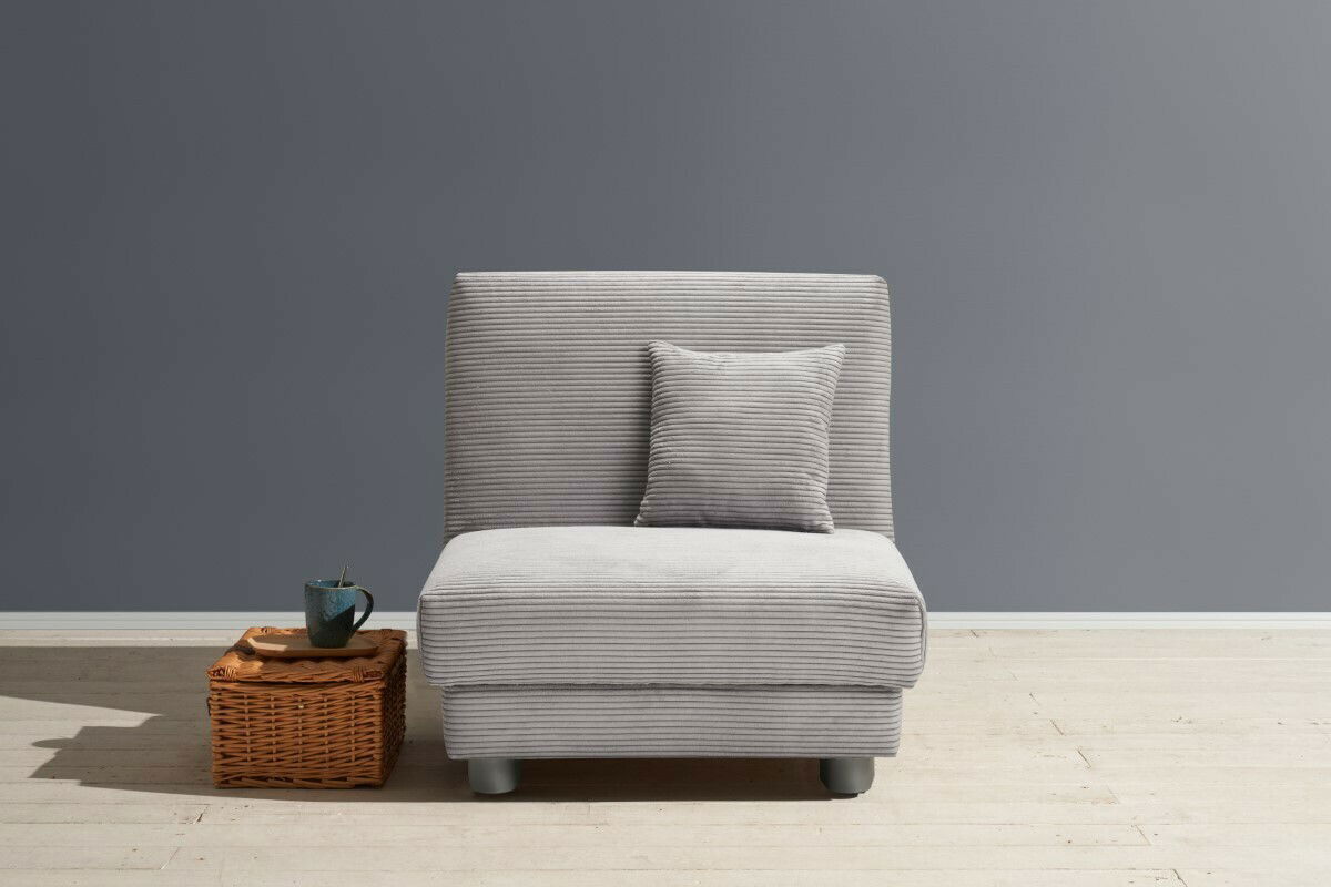 Grauer Funktionssessel mit Kissen, frontal fotografiert, neben einem kleinen Korbtisch mit Tasse.