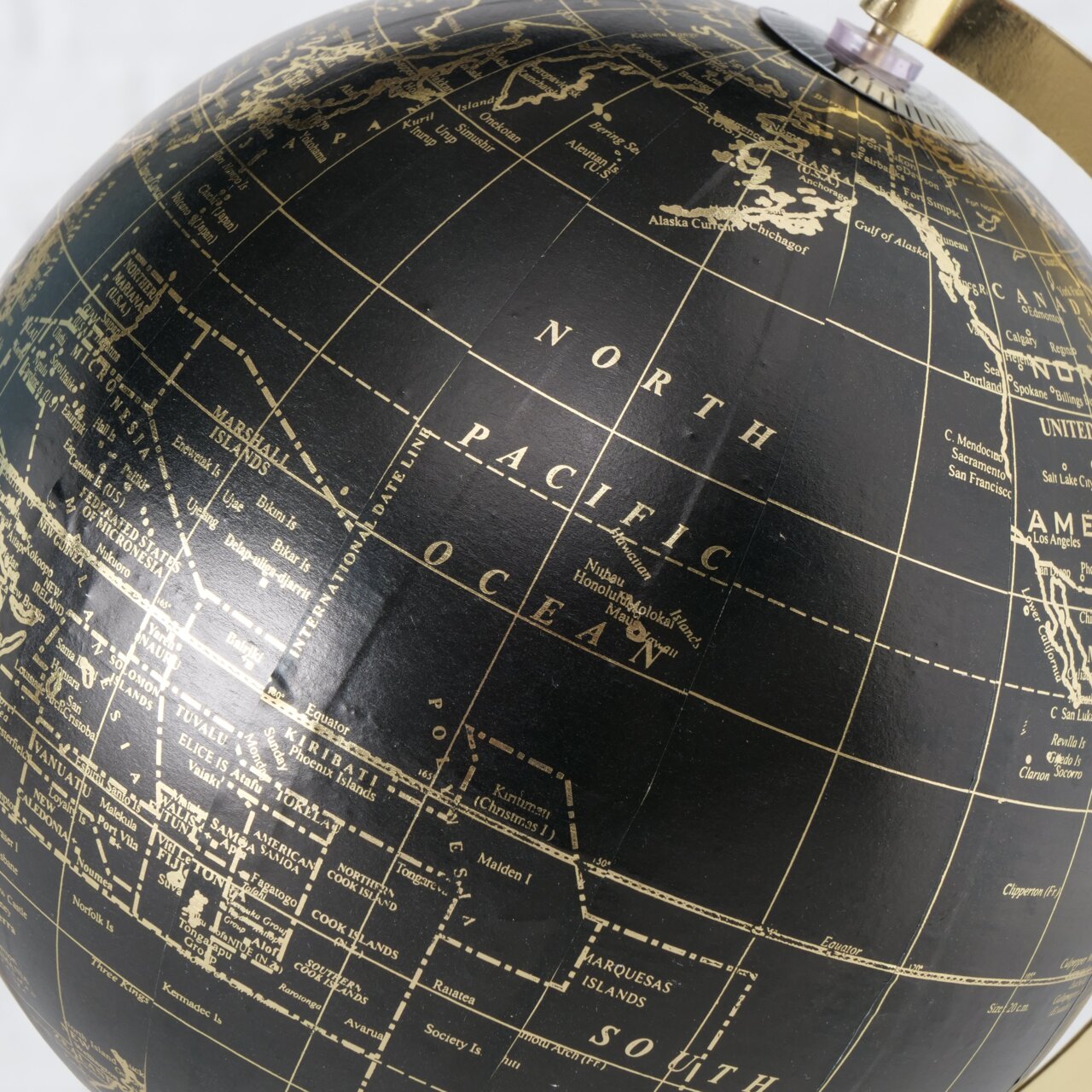 Nahaufnahme eines dekorativen Globus mit schwarzem Hintergrund und goldenen geografischen Details, Perspektive von schräg oben.