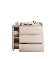 Wickelkommode in Beige mit drei Schubladen und offenem Seitenregal, oben Wickelauflage mit Stofftier; Frontansicht leicht von links auf weißem Hintergrund