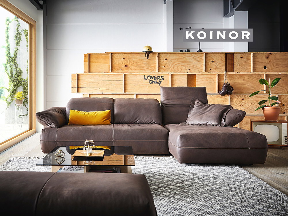 Modernes Koinor-Ledersofa in stilvollem Loft-Ambiente mit Holzwand.