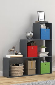 Modernes, dunkelgraues Stufenregal mit offenen Fächern und farbigen Aufbewahrungsboxen (blau, rot, grün) sowie Deko und Büchern, fotografiert in leichter Seitenansicht von vorne.