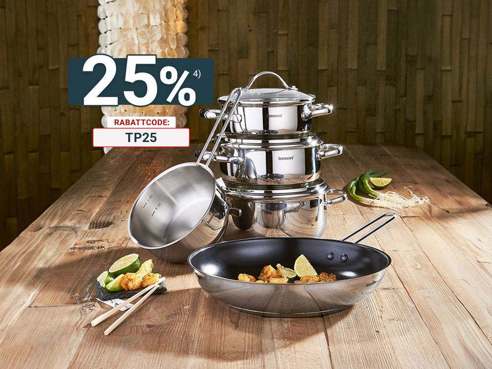 Edelstahl-Topfset und Pfanne auf Holztisch, dekoriert mit Speisen, Limetten und Gemüse in warm beleuchteter Küche