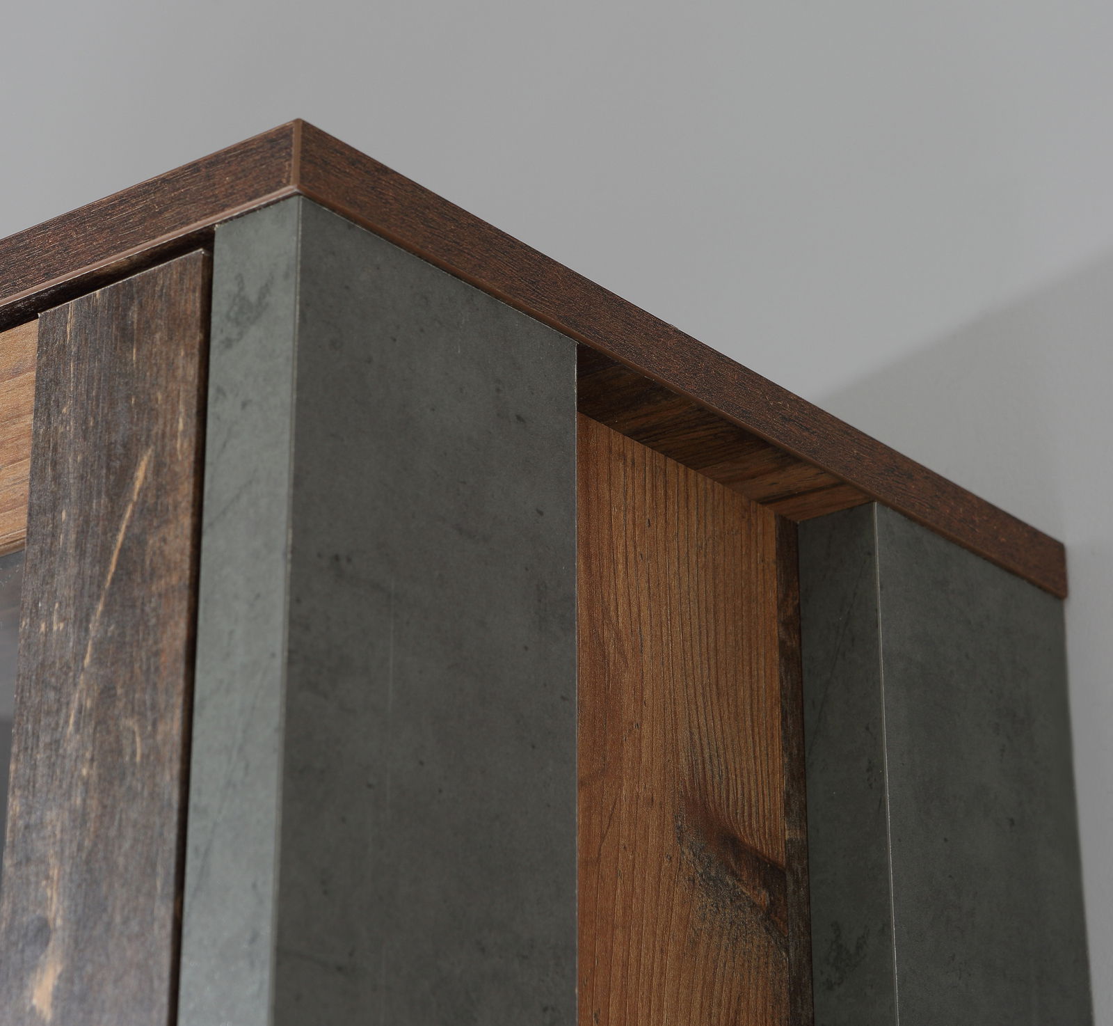 Nahaufnahme der Oberkante eines Drehtürenschranks mit Holz- und Betonoptik, perspektivisch von unten aufgenommen.