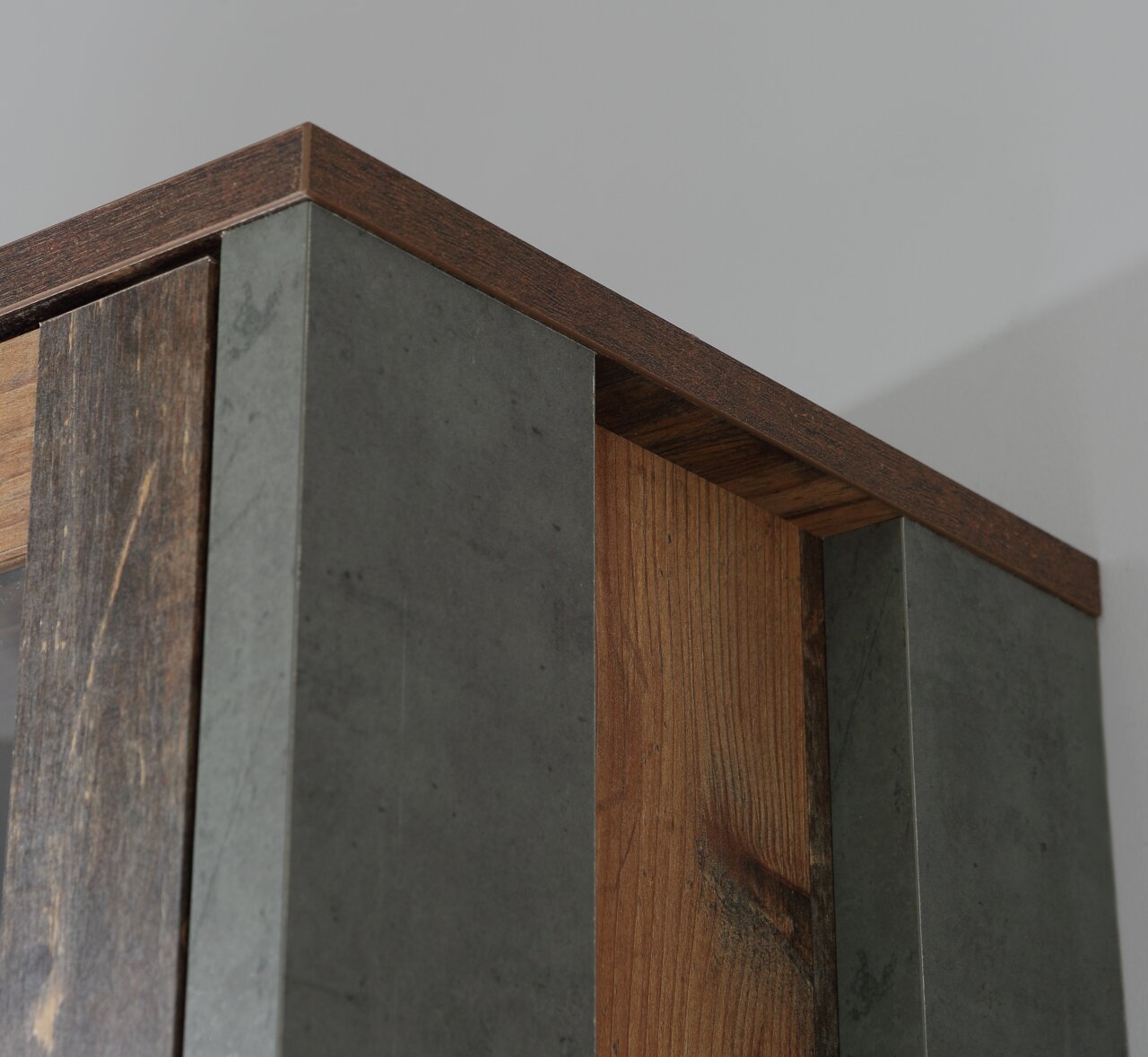 Close-up van de bovenrand van een draaideurkast met hout- en betonlook, vanuit een perspectief van onderaf gefotografeerd.