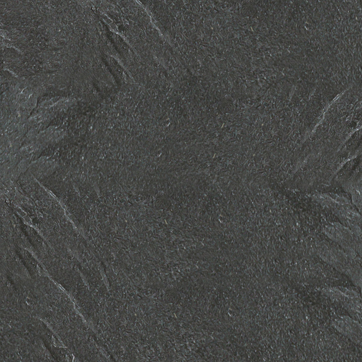 Nahaufnahme einer dunklen, strukturierten Oberfläche, möglicherweise eine Tischplatte aus Stein oder Schiefer.