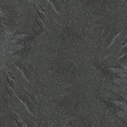 Nahaufnahme einer dunklen, strukturierten Oberfläche, möglicherweise eine Tischplatte aus Stein oder Schiefer.