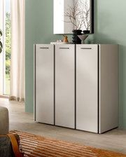 Modernes, weißes Sideboard mit drei Türen und schwarzen Griffen vor grüner Wand, dekoriert mit Vasen und Spiegel; Perspektive: frontale Ansicht in leichtem Winkel von links