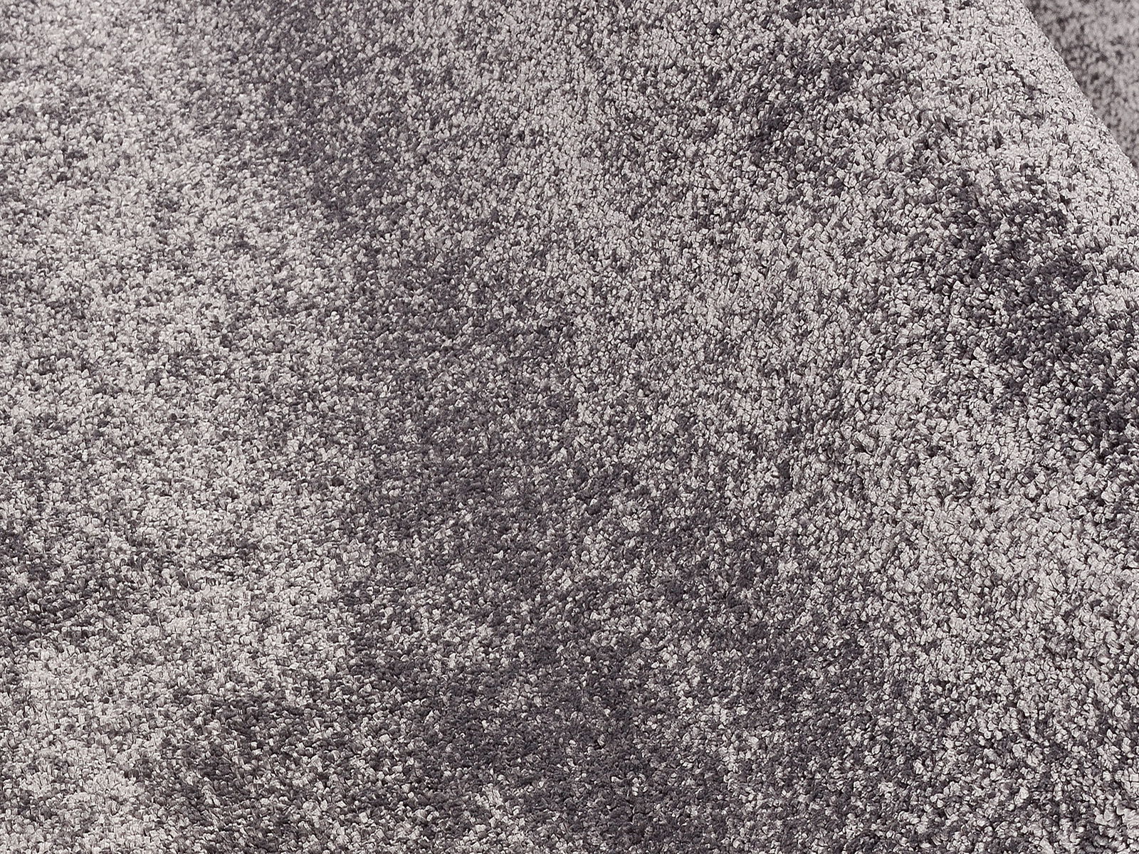 Nahaufnahme eines grauen Uni-Teppichs mit weicher Textur, perspektivisch von oben fotografiert.