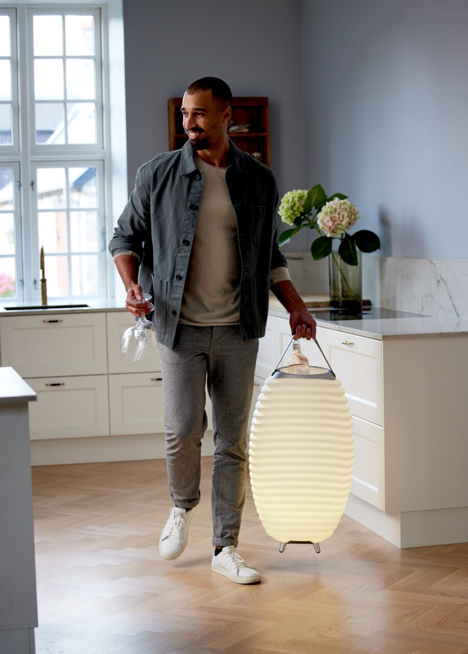 Man in een moderne keuken met een felle acculamp met luidspreker, zijaanzicht.