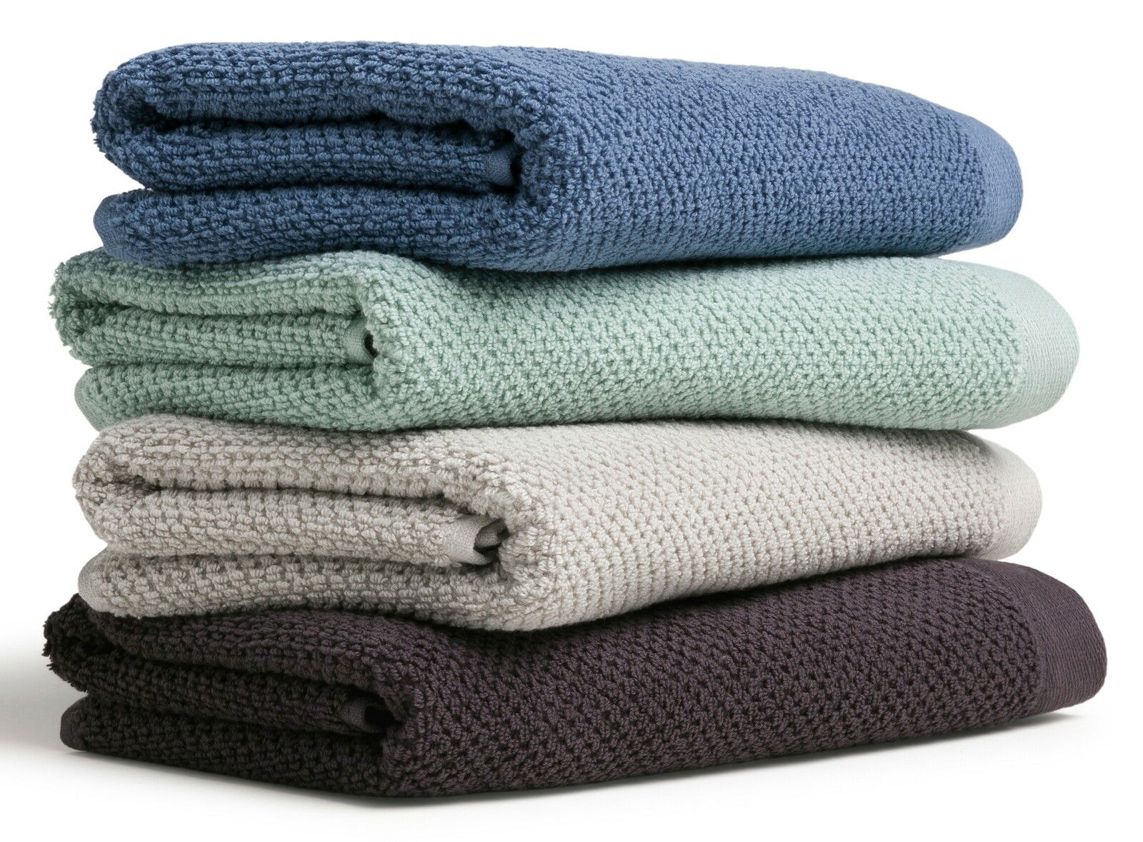 Ein Stapel von vier gefalteten Handtüchern in verschiedenen Farben: Blau, Grün, Beige und Dunkelbraun, seitlich betrachtet.