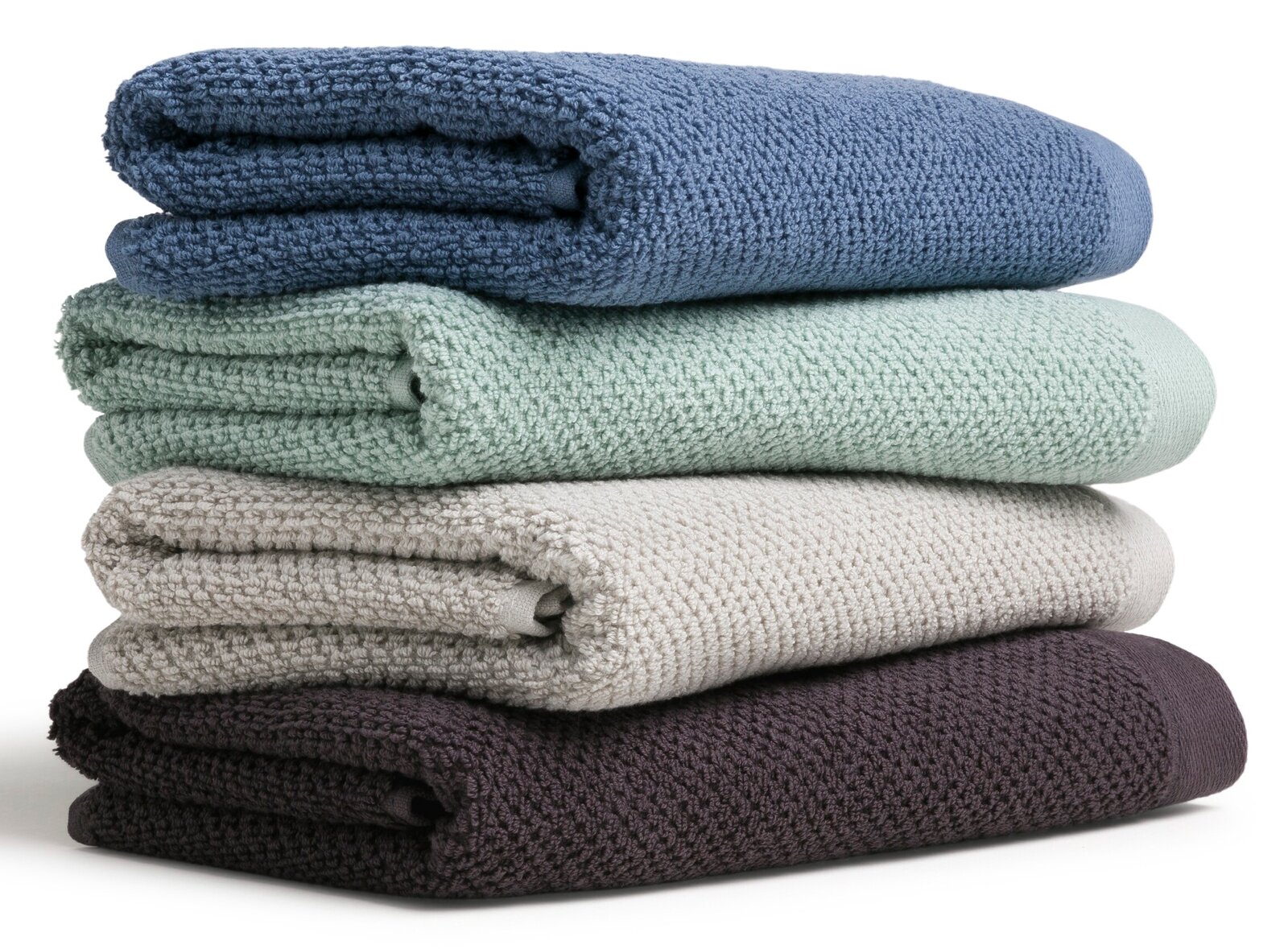 Ein Stapel von vier gefalteten Handtüchern in verschiedenen Farben: Blau, Grün, Beige und Dunkelbraun, seitlich betrachtet.