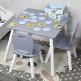 Grauer Kindertisch mit zwei Stühlen, von oben fotografiert, mit einem Memo-Spiel darauf.