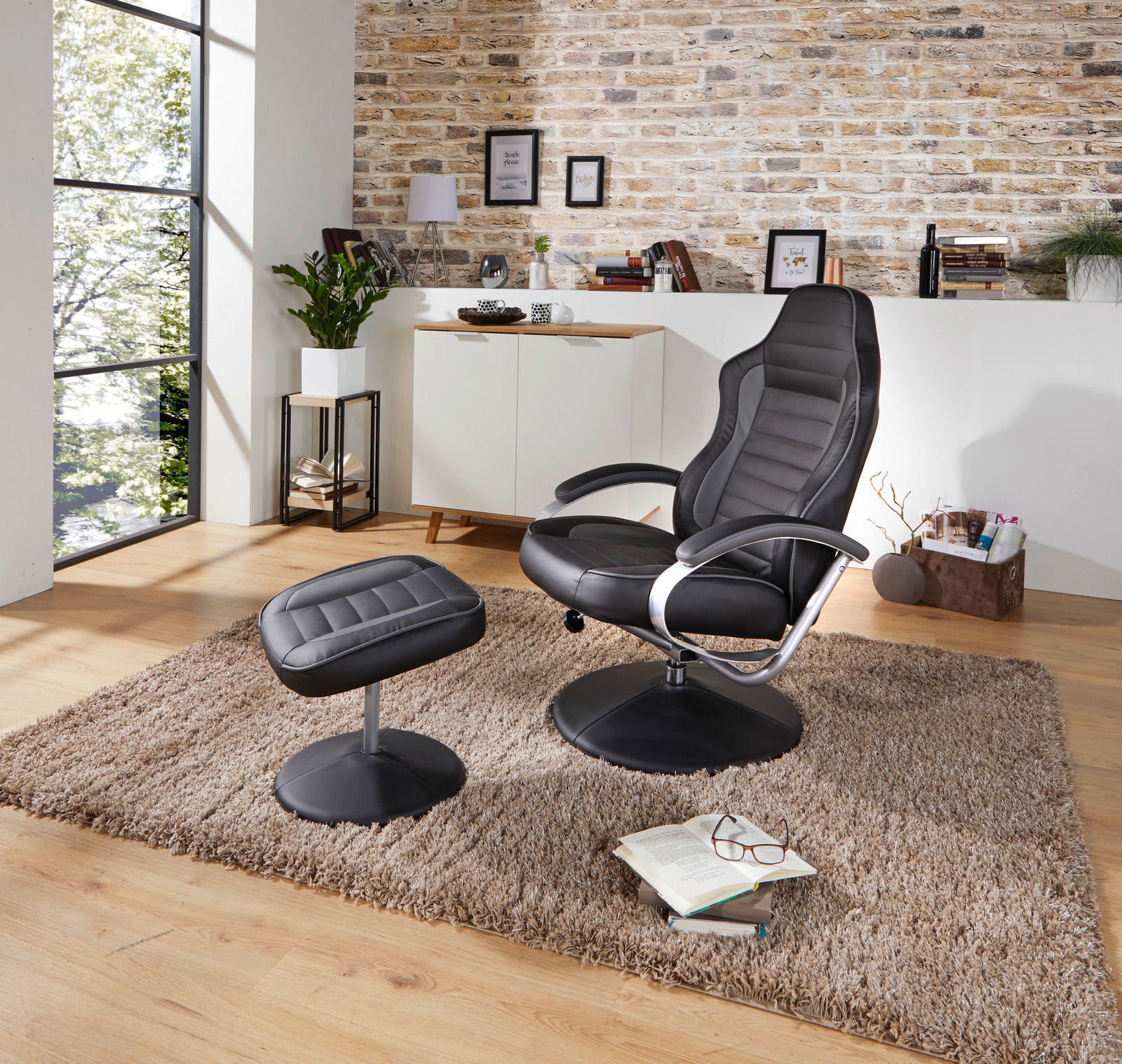 Moderner schwarzer Fernsehsessel mit passendem Hocker in einem stilvoll eingerichteten Wohnzimmer, seitliche Perspektive.