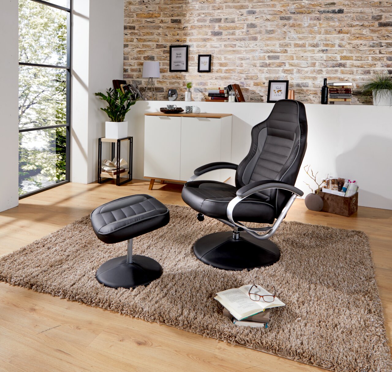 Moderner schwarzer Fernsehsessel mit passendem Hocker in einem stilvoll eingerichteten Wohnzimmer, seitliche Perspektive.