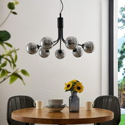 Moderne Hängeleuchte mit mehreren kugelförmigen Glühbirnen, von unten betrachtet über einem Esstisch mit Blumen und Geschirr.