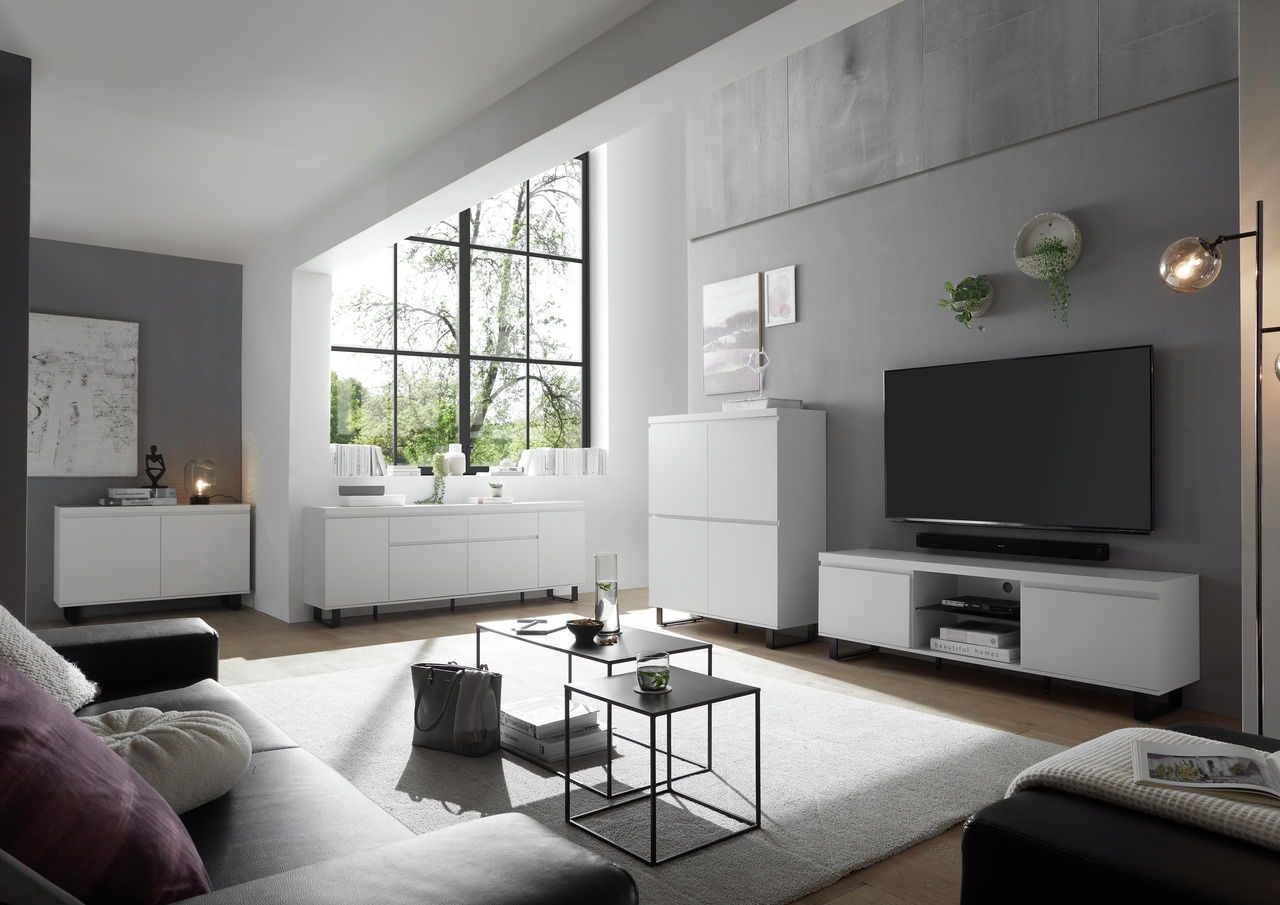 Moderne Wohnzimmermöbel in Weiß, bestehend aus TV-Lowboard, Sideboard und Highboard, in einem hellen Raum mit großen Fenstern, seitliche Perspektive.