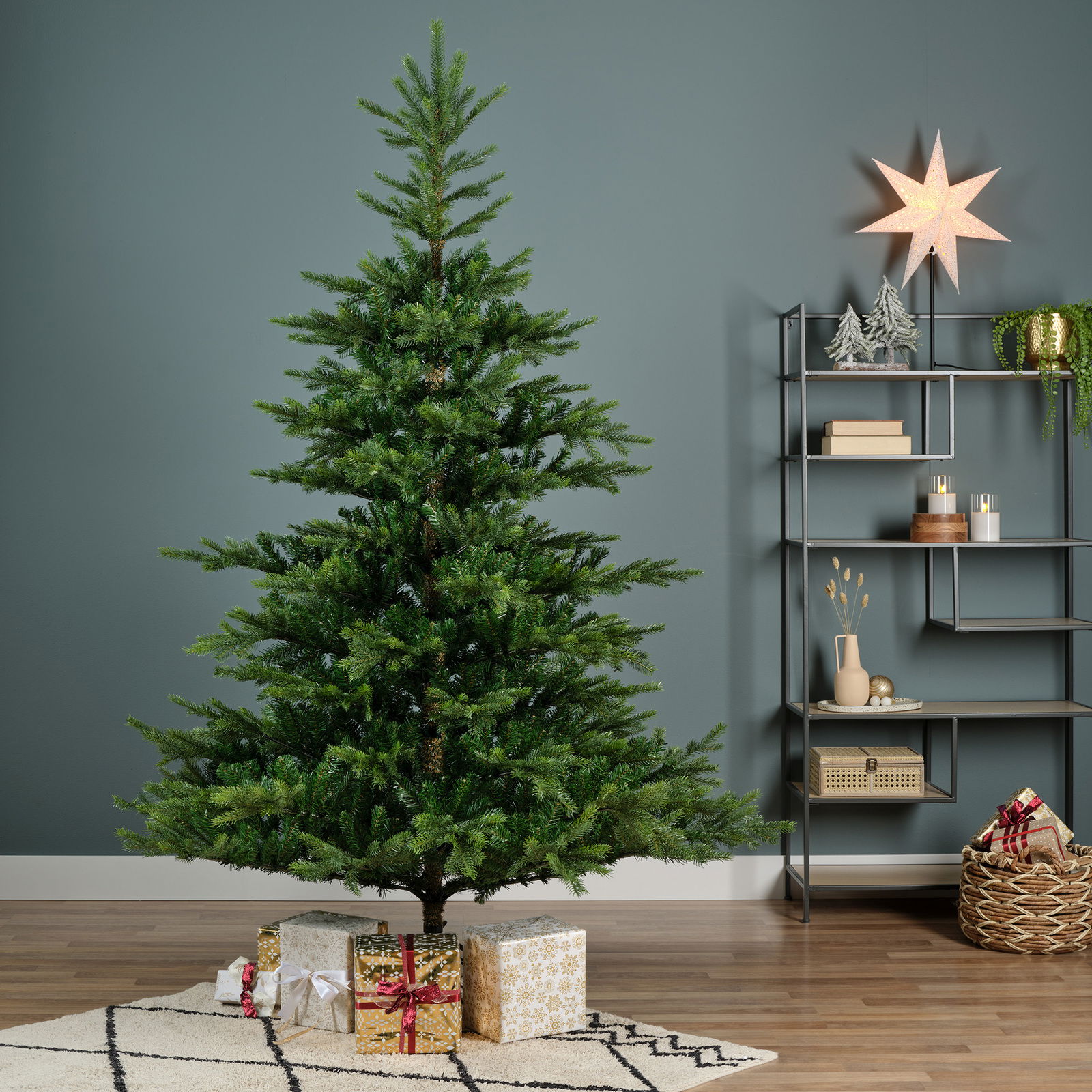 Künstlicher Weihnachtsbaum mit einer Höhe von 210 cm und einem Durchmesser von 150 cm, dekoriert mit Geschenken darunter, in einem modernen Wohnzimmer mit seitlicher Perspektive.