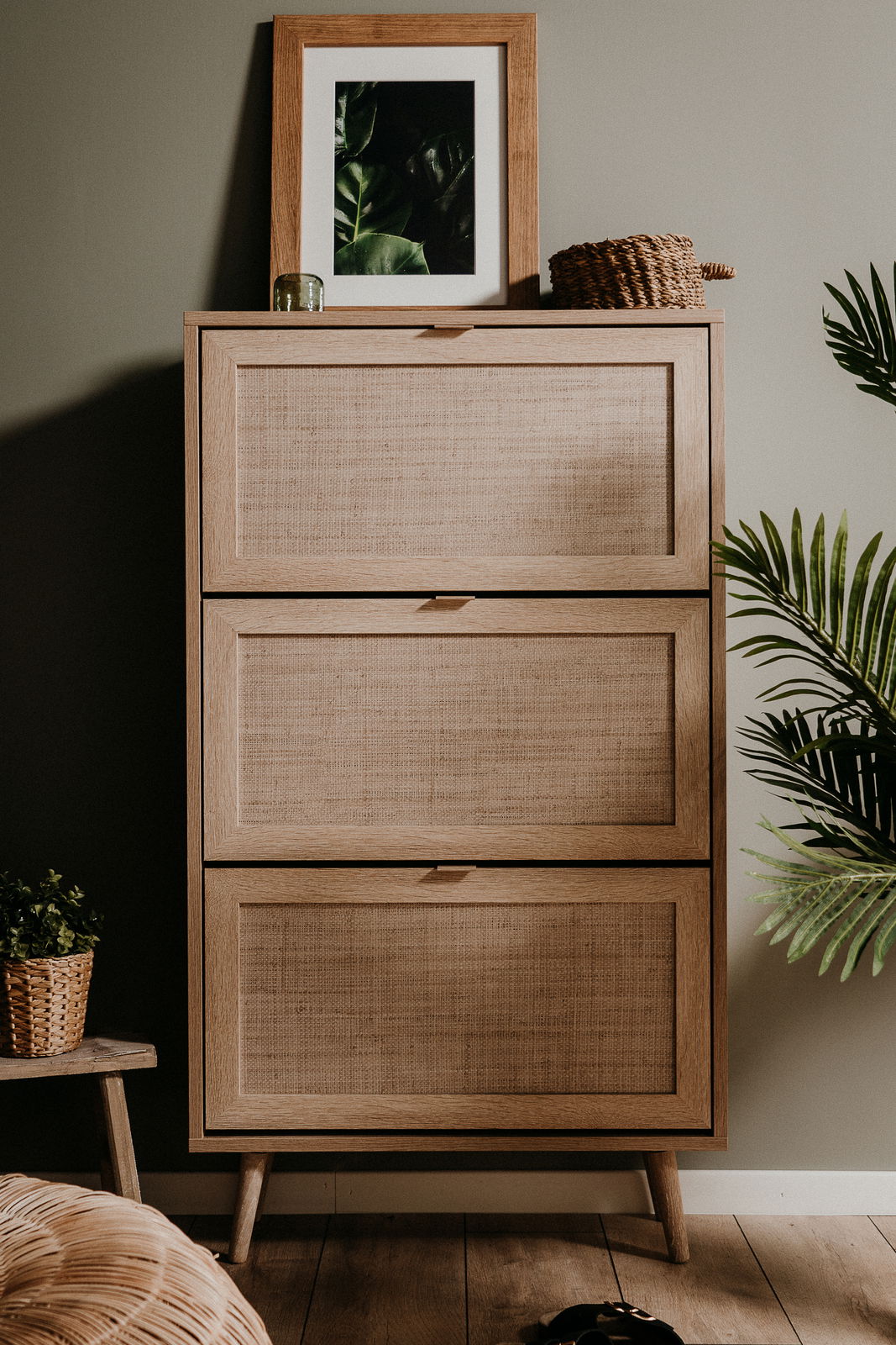 Schuhkipper aus Holz mit drei Klappen, dekoriert mit einem gerahmten Bild und einem Korb, frontal fotografiert.