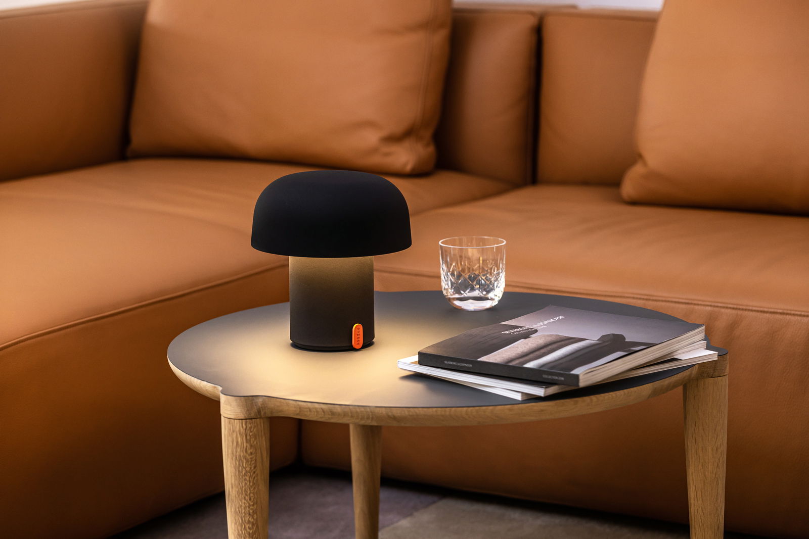 Sensa Anthracitekooduu LED-Akkuleuchte auf einem Tisch in einem gemütlichen Wohnzimmer, seitliche Perspektive