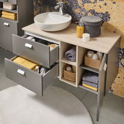 Modernes Waschtisch-Set mit grauen Schubladen und offenen Regalfächern, gefüllt mit Handtüchern und Pflegeprodukten, aus der Vogelperspektive.