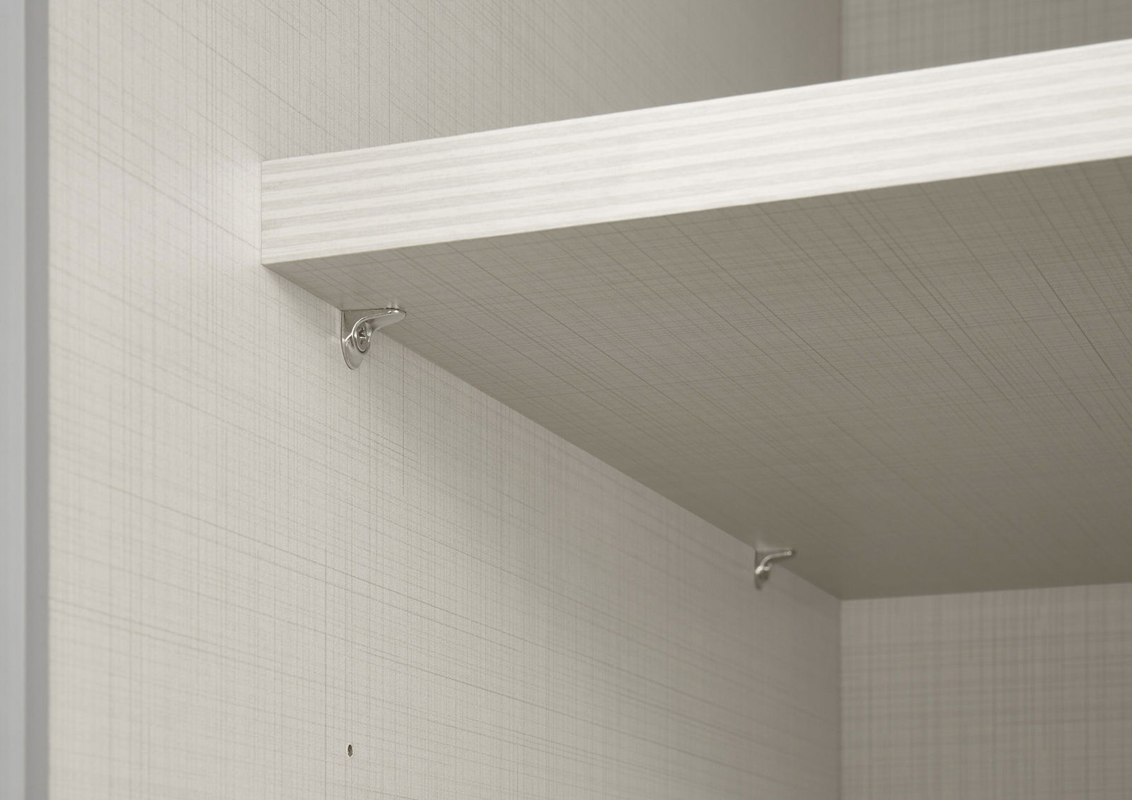 Nahaufnahme eines Schwebetürenschranks mit einem Regalbrett und silbernen Halterungen, seitliche Perspektive.