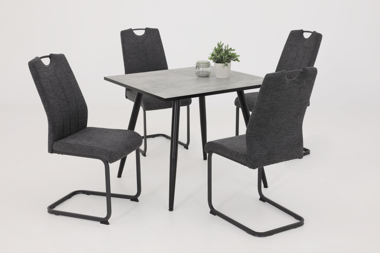 Vier graue Schwingstühle um einen quadratischen Tisch mit schwarzem Gestell, seitliche Perspektive.