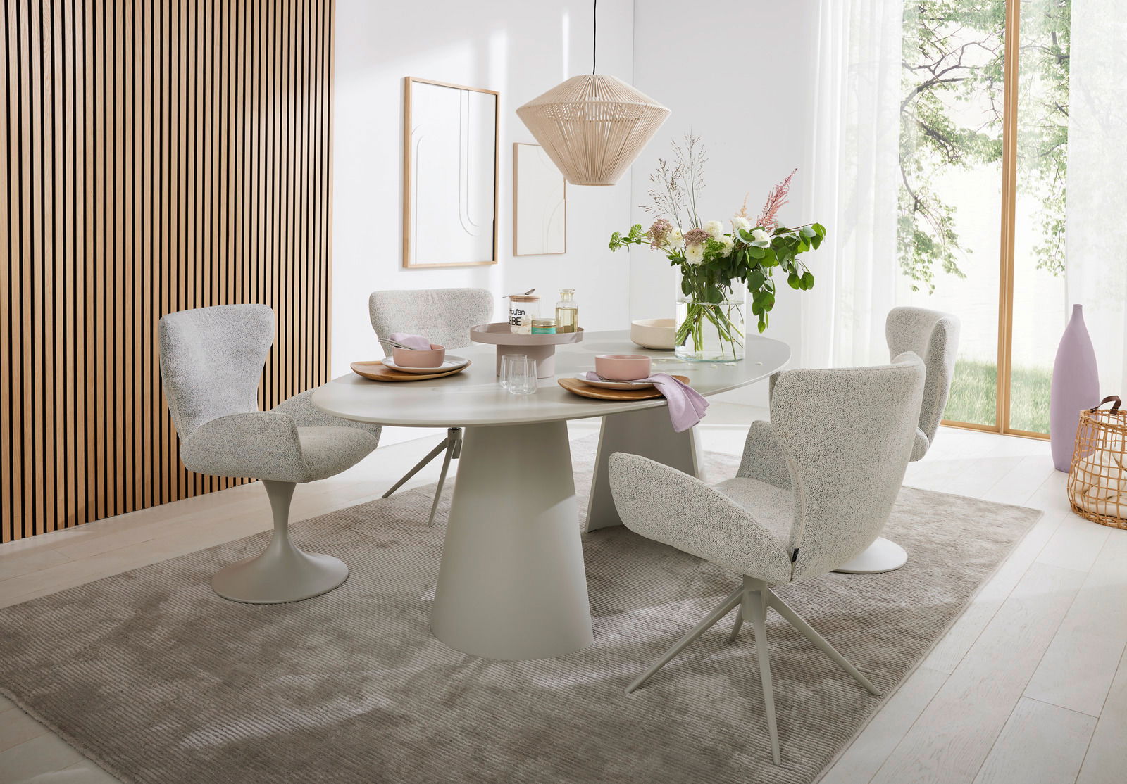 Moderner Essbereich mit rundem Esstisch und vier gepolsterten Armlehnstühlen in einem hellen Raum mit Holzverkleidung und großen Fenstern, seitliche Perspektive.