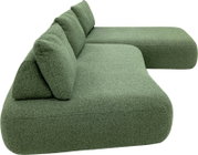 Grünes, modular wirkendes Polster-Sofa mit Chaiselongue rechts und zwei Rückenkissen, Ansicht schräg von hinten/seitlich vor weißem Hintergrund