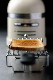 Nahaufnahme eines 2-er Toasters mit einem frisch gerösteten Toastbrot im Vordergrund. Der Toaster ist in einem eleganten Design gehalten.