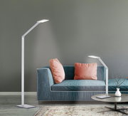 Moderne Tischleuchte aus Aluminium, seitliche Perspektive, neben einem Sofa mit rosa Kissen.