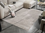 Designer Teppich in einem modernen Wohnzimmer, fotografiert aus einer leicht erhöhten Perspektive. Der Teppich liegt auf einem dunklen Holzboden, umgeben von einem Sofa, einem Tisch und einer Gitarre.