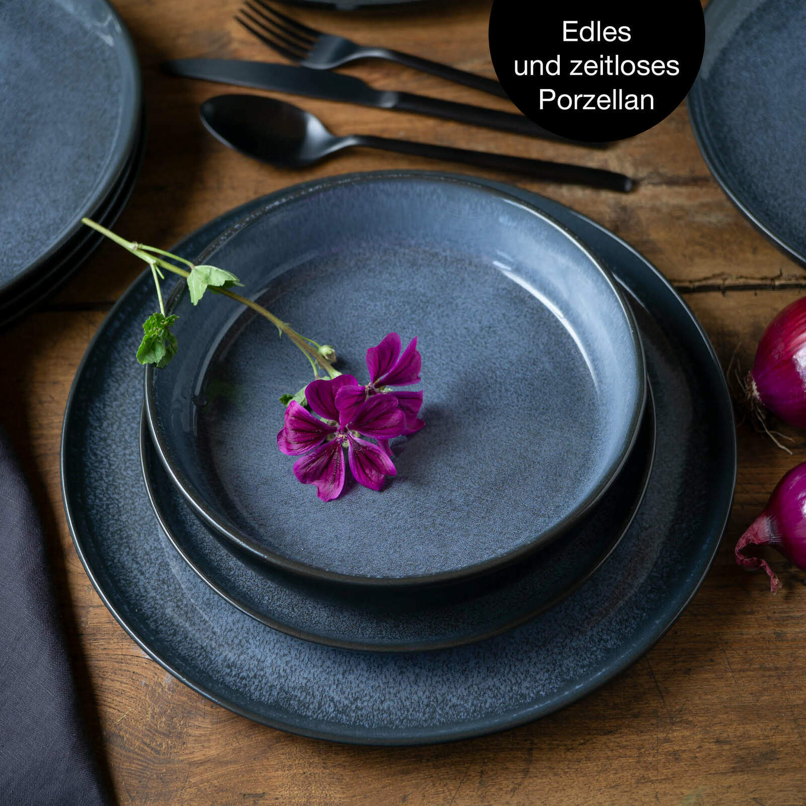 Vogelperspektive auf ein elegantes, blaues Tafelservice aus Porzellan mit einer violetten Blume als Dekoration.