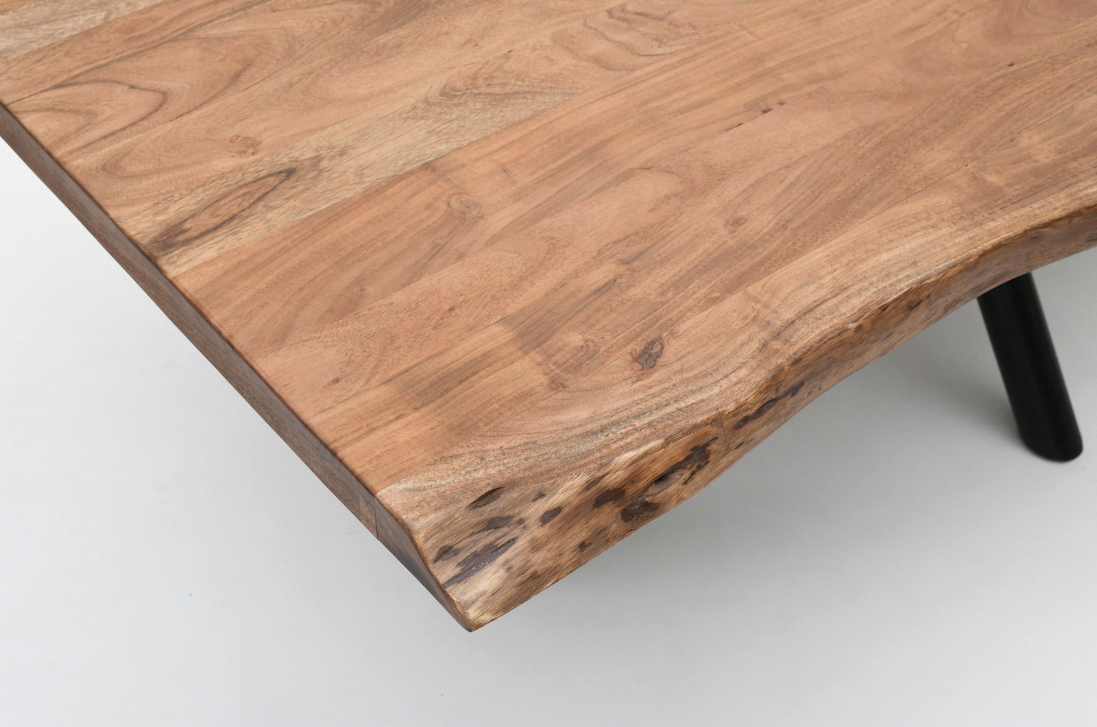 Nahaufnahme eines Esstisches aus Holz mit natürlicher Kante und schwarzem Tischbein, von oben betrachtet.