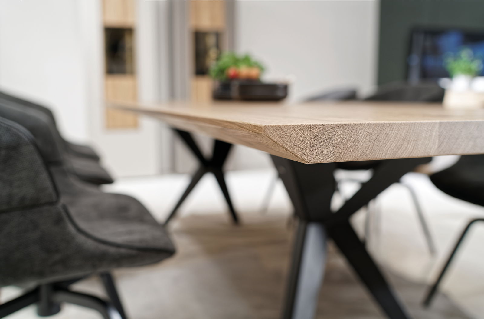 Nahaufnahme eines modernen Esstisches mit Holzplatte und schwarzen Metallbeinen, seitliche Perspektive.